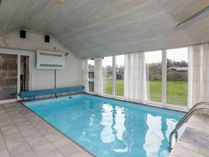 6 person holiday home in Ulfborg في Sønder Nissum: مسبح كبير في منزل به نوافذ