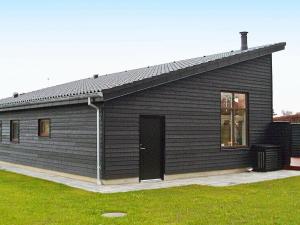 ボルコップにある6 person holiday home in B rkopの黒い扉と草原のある黒い建物