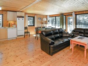 a living room with a leather couch and a kitchen at Three-Bedroom Holiday home in Blokhus 21 in Blokhus
