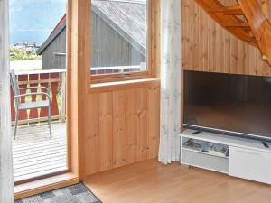 a living room with a large tv and a balcony at Holiday home Måndalen in Sæbø