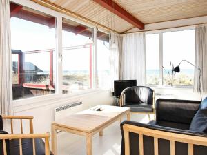 - un salon avec une table, des chaises et des fenêtres dans l'établissement Three-Bedroom Holiday home in Løkken 65, à Grønhøj