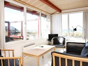 GrønhøjにあるThree-Bedroom Holiday home in Løkken 65のリビングルーム(テーブル、椅子、窓付)