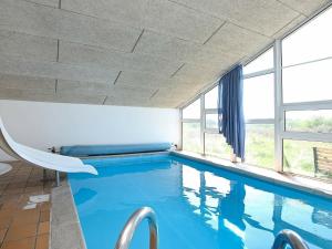 einen Pool mit blauem Wasser in einem Zimmer mit Fenstern in der Unterkunft Five-Bedroom Holiday home in Hjørring 2 in Lønstrup