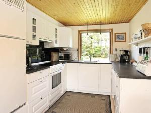 Jerupにある8 person holiday home in Jerupの白いキャビネットと木製の天井が備わるキッチン