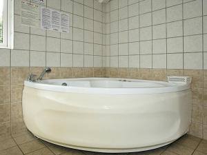 y baño alicatado con bañera blanca. en 8 person holiday home in Hadsund, en Øster Hurup