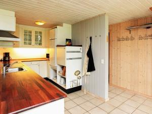 DannemareにあるHoliday Home Holdvejのキッチン(白い冷蔵庫、木製キャビネット付)