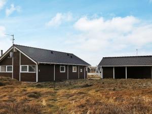 a black house on a hill next to a building at 6 person holiday home in Harbo re in Harboør