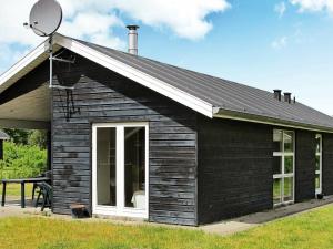 una pequeña casa negra con satélite en 6 person holiday home in Hals en Hals