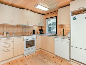 ブロックフスにあるThree-Bedroom Holiday home in Blokhus 21の木製の天井、白い家電製品付きのキッチン