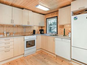 cocina con electrodomésticos blancos y techo de madera en Three-Bedroom Holiday home in Blokhus 21, en Blokhus