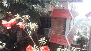 a building with a red roof and some flowers at Shamrock Holiday Home in Munnar