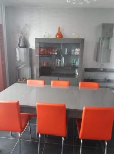 a kitchen with orange chairs and a large table at El Corazon in Stavelot