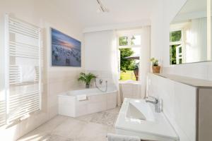 Baño blanco con bañera y lavamanos en Fehmarn Mein Urlaub, en Fehmarn