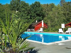 a swimming pool with a red barn and a red house at 6 person holiday home in Nex in Snogebæk