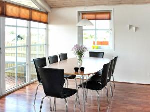 a dining room with a table and black chairs at 8 person holiday home in R m in Bolilmark