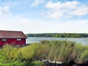 a red barn in the grass next to a body of water at 5 person holiday home in V DD in Veda