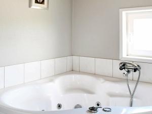 baño con bañera blanca y ventana en 8 person holiday home in R m en Bolilmark