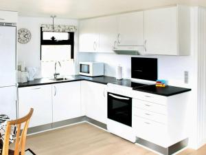 a kitchen with white cabinets and a black counter top at 6 person holiday home in R m in Bolilmark