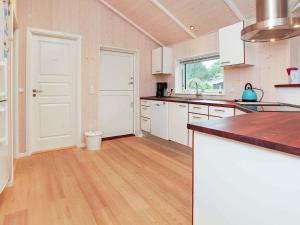 Il comprend une cuisine avec des placards blancs et du parquet. dans l'établissement 8 person holiday home in H rve, à Hørve