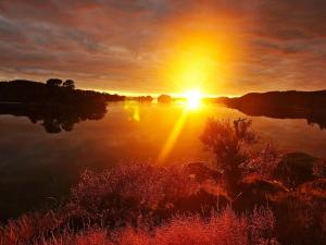 a sunset on a lake with the sun setting at 4 person holiday home in Austrheim in Bergsviki