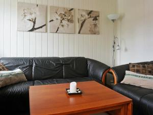 a living room with a black leather couch and a table at 4 person holiday home in Austrheim in Bergsviki