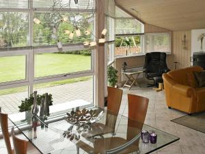 Three-Bedroom Holiday home in Storvorde 19 في Egense: غرفة معيشة مع طاولة وكراسي زجاجية