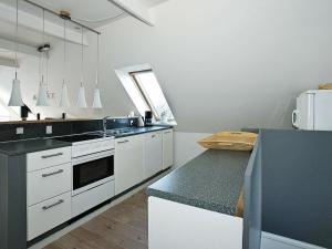cocina con armarios blancos y encimera negra en Three-Bedroom Holiday home in Vestervig 14 en Vestervig