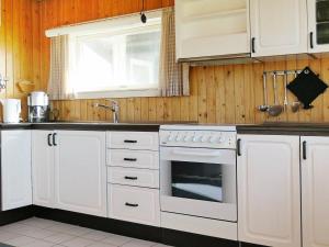 a kitchen with white cabinets and a sink and a stove at 8 person holiday home in Harbo re in Vrist