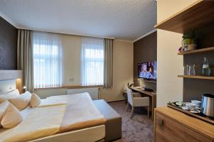 Habitación de hotel con cama, escritorio y TV. en Ambient Hotel Zum Schwan en Gelsenkirchen