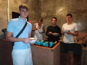 a group of men standing around a table eating food at Phayam Hostel in Ko Phayam