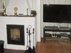 a living room with a fireplace and a flat screen tv at Holiday Home Brunkelstorp in Osby