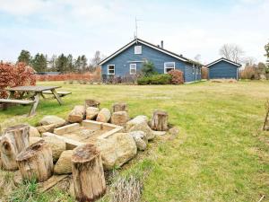 una mesa de picnic y troncos en un campo con una casa en Holiday home Sæby II, en Saeby