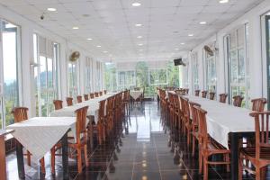 Punsisi Resort - Adam's Peak في نالاثانيا: صف من الطاولات والكراسي في غرفة بها نوافذ