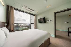 a bedroom with a large white bed and a large window at Sunrise Hotel Jungmun Branch in Seogwipo