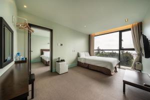 a bedroom with two beds and a large window at Sunrise Hotel Jungmun Branch in Seogwipo