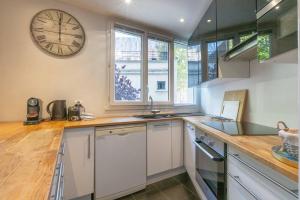 a kitchen with a large clock on the wall at Paris City - Spacious 3 rooms flat for families - 3 minutes from metro station in Paris