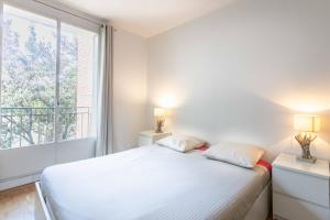 a white bedroom with a bed and a window at Paris City - Spacious 3 rooms flat for families - 3 minutes from metro station in Paris