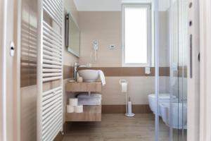 uma casa de banho com um lavatório, um WC e uma janela. em BORGO BEATRICE em Tignale