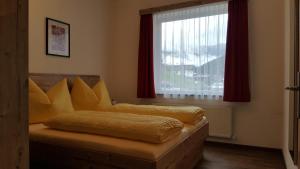 um quarto com uma cama com almofadas amarelas e uma janela em Appartement Juns em Tux