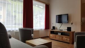 a living room with a flat screen tv and red curtains at Appartement Juns in Tux