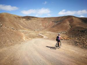 a person riding a bike down a dirt road at Villa Shepherd Lajares - LUXURY VILLA FUERTEVENTURA in Lajares