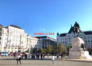 Un gruppo di persone che camminano per una città con una statua di Anabelle Bed and Breakfast a Budapest