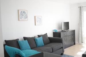 a living room with a gray couch and blue pillows at The Sands Hotel in Cockburn Town