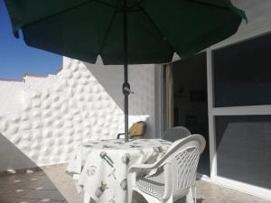 una mesa con una sombrilla verde en el patio en Casa Hibiscus sehr schönes Appartment zum relaxen, en Costa Calma