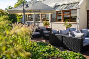 une terrasse avec des canapés et un parasol en face d'un bâtiment dans l'établissement Stadt-gut-Hotel Filderhotel, à Ostfildern