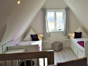 レリクにあるModern Detached Holiday Home in Rerik with Saunaのベッド2台と窓が備わる屋根裏部屋です。