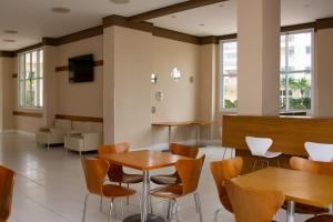 a waiting room with wooden tables and chairs at Ap 3 qtos 2vg gar cob Twice Guaruja in Guarujá