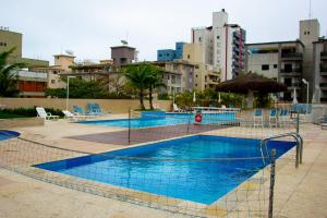 a large swimming pool with blue chairs and umbrellas at Ap 3 qtos 2vg gar cob Twice Guaruja in Guarujá
