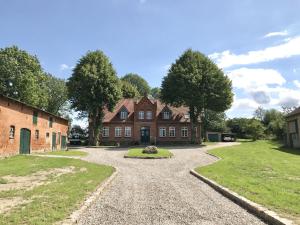a large brick house with a gravel driveway at Im Gutshofpark in Lübberstorf