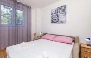 Schlafzimmer mit einem Bett mit rosa Kissen und einem Fenster in der Unterkunft Apartman Nina 1 in Senj